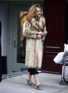 a woman in a fur coat is walking down the street