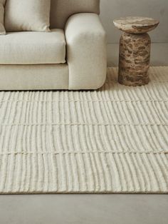 a living room with a couch, table and rugs on the floor in front of it