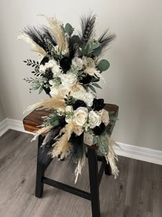 an arrangement of flowers and feathers on a wooden bench in the corner of a room