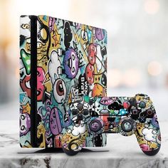 a video game console and controller covered in colorful sticker art next to each other