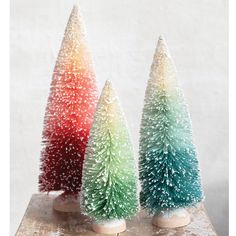 three small christmas trees sitting on top of a wooden table