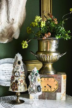 there is a small christmas tree next to a clock and other decorations on the table