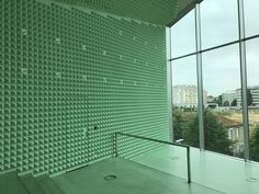 an empty stairwell in front of a large window with green glass covering the entire wall