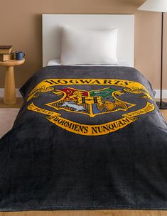 a bed with a harry potter blanket on top of it next to a night stand