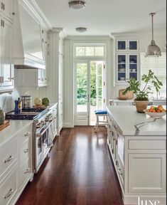 a large kitchen with white cabinets and wood flooring, along with an open door leading to the outside