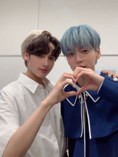 two young men standing next to each other making a heart shape with their hands in front of them