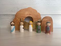 small wooden figurines in front of a nativity scene with angel and dove