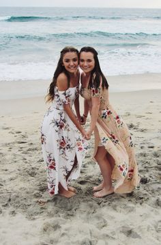 two girls standing on the beach with their arms around each other