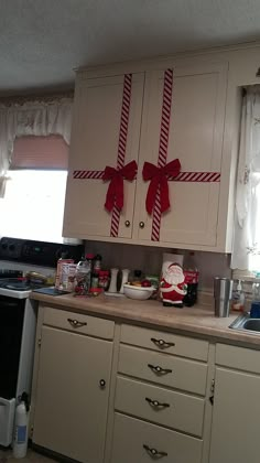 a kitchen with white cabinets and red bows on the back of it's doors