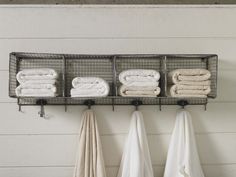 towels are hanging on the rack in front of some iron racks with hooks holding them