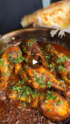 chicken curry in a pan being served with bread on the side and garnished with parsley