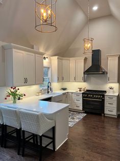 a large kitchen with white cabinets and an island in the middle is lit by two pendant lights