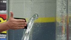 a person is giving a thumbs up while standing in front of a fountain with water running down it