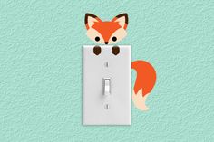 a light switch cover with an orange fox on it's side and a green background