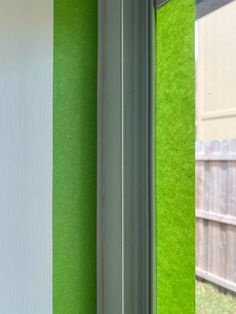 an open window with green and white stripes on the wall next to a wooden fence