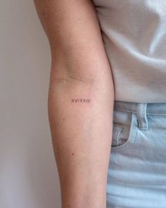 a woman's arm with the word xxvix tattooed on her left arm