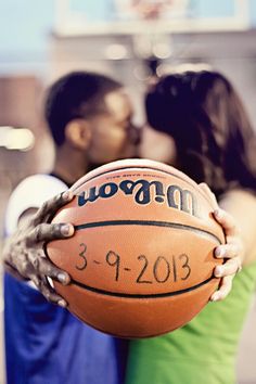 a man and woman kissing while holding a basketball