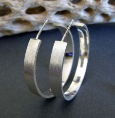 "Modern open hoop earrings handmade from sterling silver. These simple earrings will go great with everything. The Details ∞ Artisan handmade jewelry ∞ Hand formed sterling silver hoops about 1\" (or 25mm) diameter ∞ 4mm width, 1mm thick ∞ Brushed finish ∞ Sterling silver clutch earring backs ∞ Made to order ∞ Gift box included ∞ Made in the USA Check out our huge selection of stud earrings here... https://www.etsy.com/shop/PoseidonsBooty?search_query=stud+earrings VISIT OUR SHOP: http://www.Pos Modern Handmade Hoop Earrings For Anniversary, Handmade Modern Hoop Earrings For Anniversary, Modern Sterling Silver Hoop Earrings With Simple Design, Modern Hand Forged Hoop Earrings, Modern Hand Forged Silver Hoop Earrings, Modern Hand-forged Silver Hoop Earrings, Small Silver Contemporary Hoop Earrings, Contemporary Silver Small Hoop Earrings, Contemporary Small Silver Hoop Earrings