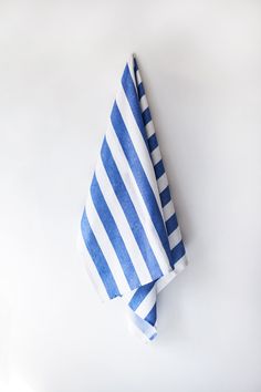 two blue and white striped napkins sitting on top of each other in front of a white wall