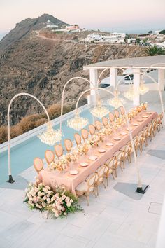 a long table is set up with flowers and candles for an outdoor wedding reception overlooking the ocean