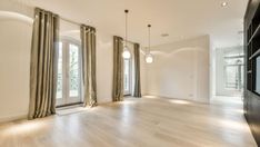 an empty living room with wood floors and large windows