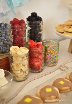 cookies, fruit and other snacks are on display in glass jars next to each other