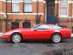 a red sports car parked in front of a brick building