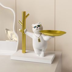 a white bear holding a gold plate on top of a table next to a mirror