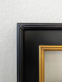 a black and gold frame with a white wall in the background