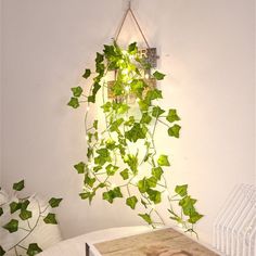 a table with a laptop on top of it next to a plant hanging from the wall