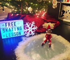 an elf is sitting on the floor next to a sign that says free skating lesson