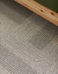 a close up of a rug on the floor with a wooden frame and green wall in the background