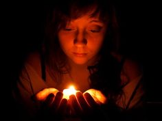 a woman holding a lit candle in her hands