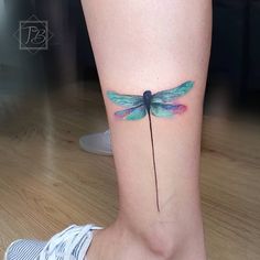 a woman's foot with a tattoo of a blue dragonfly on the ankle