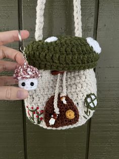 a hand holding a small crocheted purse with a bear and mushroom on it