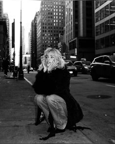 black and white photograph of woman sitting on curb talking on cell phone