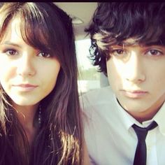 a man and woman are sitting in the back seat of a car looking at the camera