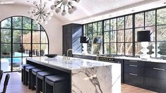 a large kitchen with marble counter tops and black cabinetry next to an outdoor swimming pool