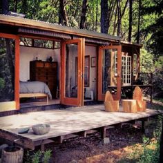 a small cabin in the woods with its doors open and furniture on the ground outside