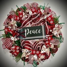 a wreath with the word peace written on it in white and red ribbon, surrounded by christmas decorations