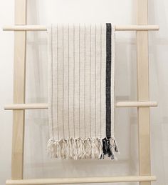 a white and black towel hanging on a wooden ladder