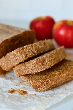 slices of bread sitting on top of a piece of wax paper next to an apple