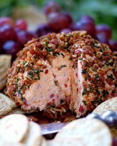 a cheese ball covered in nuts and other toppings on a plate with crackers