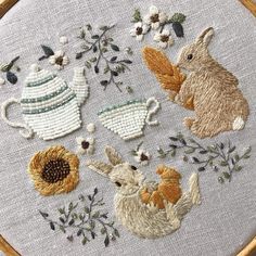 a close up of a embroidery on a piece of cloth with flowers and bunnies