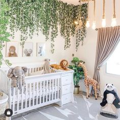 a baby's room with stuffed animals and greenery on the wall, including a crib