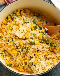 a pot filled with rice and corn on top of a table next to an onion wedge