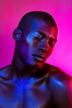 a man with his eyes closed in front of a purple and pink background, he is looking at the camera