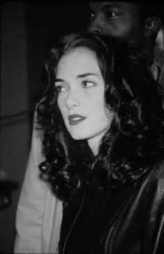 a black and white photo of a woman with long dark hair wearing a leather jacket