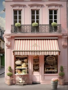 a pink store front with an awning on the top and two windows above it