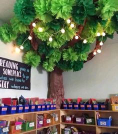 a tree with lights hanging from it's branches in a room filled with children's books